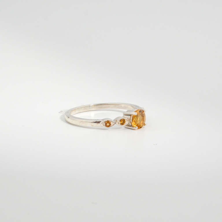 A 925 sterling silver women's solitaire ring featuring a round faceted natural yellow citrine gemstone with side stone accents.