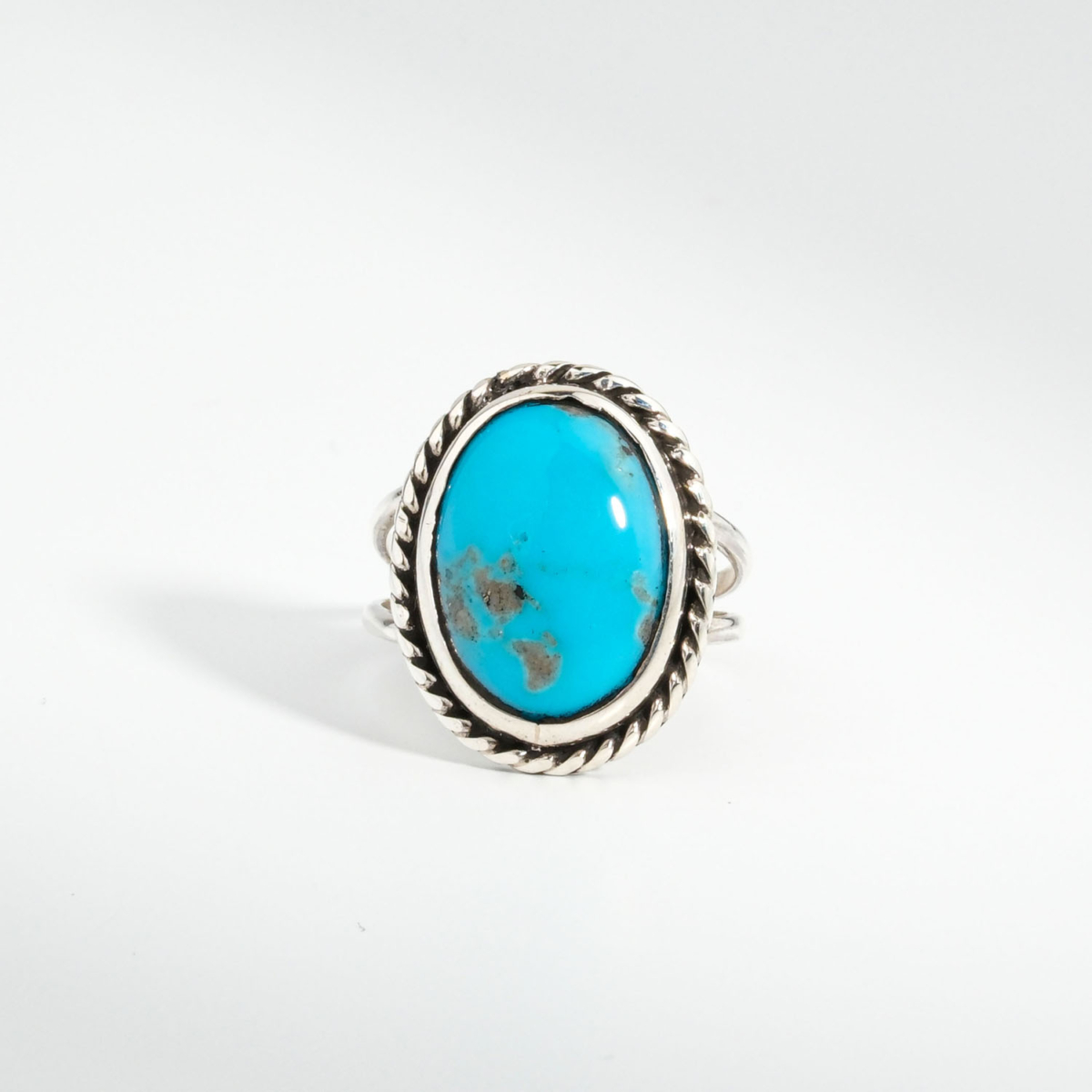 A 925 sterling silver women's ring featuring a natural oval cabochon turquoise gemstone with twisted rope silver bezel.
