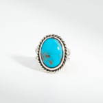 A 925 sterling silver women's ring featuring a natural oval cabochon turquoise gemstone with twisted rope silver bezel.