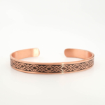 A pure copper handmade open cuff bracelet featuring engraved geometric patterns on top and Ayat al-Kursi inside.