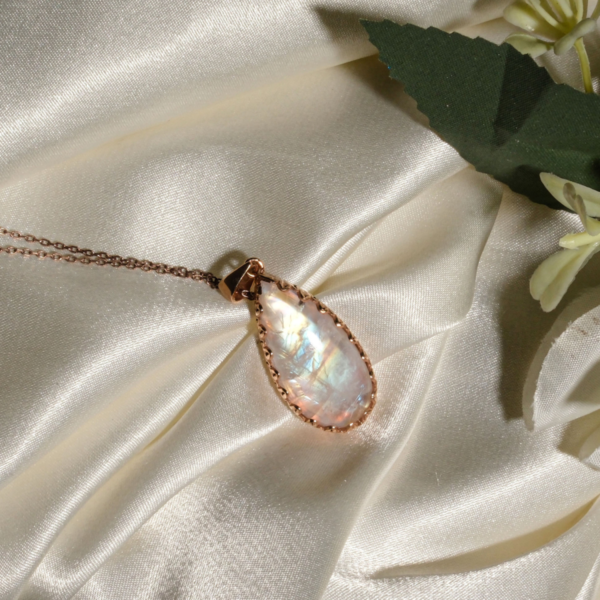 Colgante de plata 925 chapada en oro rosa con piedra luna natural en forma de gota sobre seda blanca.