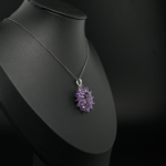 Pendentif fleur pour femme en améthyste violette naturelle fasetée et argent sterling 925 sur tissu blanc.