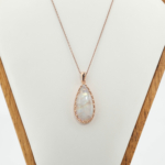 Pendentif goutte en pierre de lune naturelle et argent 925 plaqué or rose sur tissu blanc satiné.