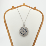 Pendentif médaillon pour femme en saphir bleu naturel et argent 925 orné de micro zircons sur tissu blanc.