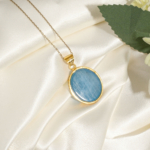 Elegant forgyldt 925 sølv halskæde til kvinder med oval naturlig lyseblå akvamarin ædelsten cabochon og emaljedetaljer.