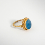 Bague pour femme en argent 925 doré sertie d'une aigue-marine bleue naturelle taillée en cabochon avec monture torsadée.