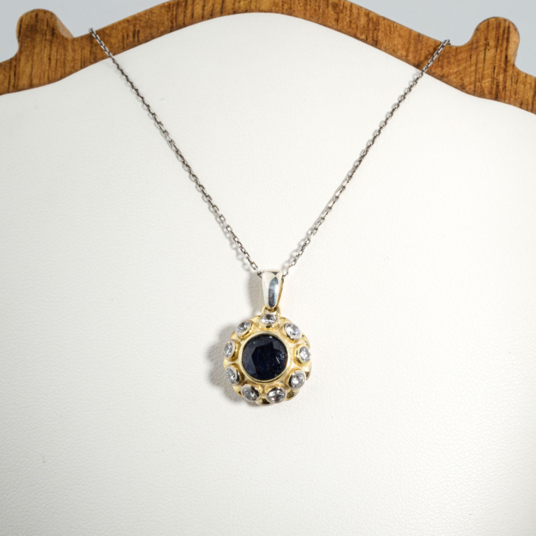 A 925 sterling silver women's pendant featuring a natural round blue sapphire gemstone surrounded by gold-plated and cubic zirconia details.