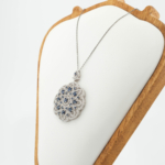 Natural deep blue faceted sapphire gemstone lace medallion pendant necklace in 925 sterling silver on white silk.