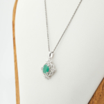 Natural green faceted oval emerald gemstone vintage baroque pendant necklace in 925 sterling silver on black background.