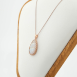 Natural teardrop rainbow moonstone pendant in 925 sterling silver rose gold plating on white silk.