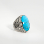 A 925 sterling silver handmade men's ring featuring a natural oval cabochon cut Nishapur turquoise gemstone with black matrix spots.