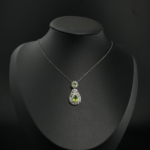 Natural light green teardrop peridot gemstone halo pendant necklace in 925 sterling silver on white silk.
