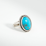 Bague pour femme en argent 925 sertie d'une turquoise naturelle taillée en cabochon avec bordure torsadée.