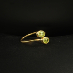A gold-plated 925 sterling silver women's bypass ring featuring two natural oval faceted green peridot gemstones in a bezel setting.