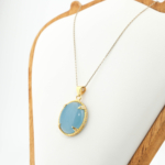 Gold plated 925 sterling silver women necklace featuring an oval cabochon natural blue aquamarine gemstone with enamel and zircon halo.