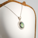 Pendentif unisex en argent 925 serti d'une nacre abalone naturelle iridescente taillée en cabochon avec bordure de zircons.