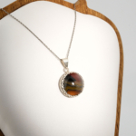 A 925 sterling silver unisex pendant featuring a natural round cabochon banded agate gemstone with scalloped bezel.