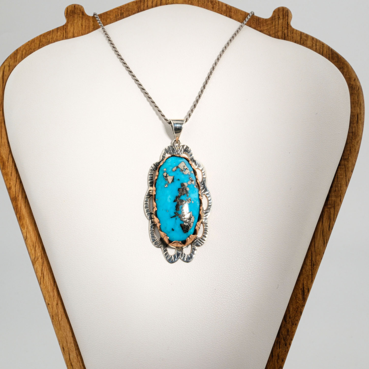 A 925 sterling silver handmade unisex pendant featuring a natural long oval cabochon cut Nishapur turquoise gemstone with pyrite matrix.