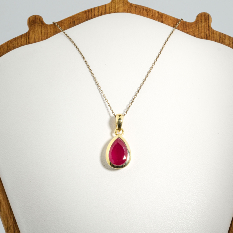 A gold-plated 925 sterling silver women's pendant featuring a natural pear-shaped faceted red ruby gemstone in a bezel setting.