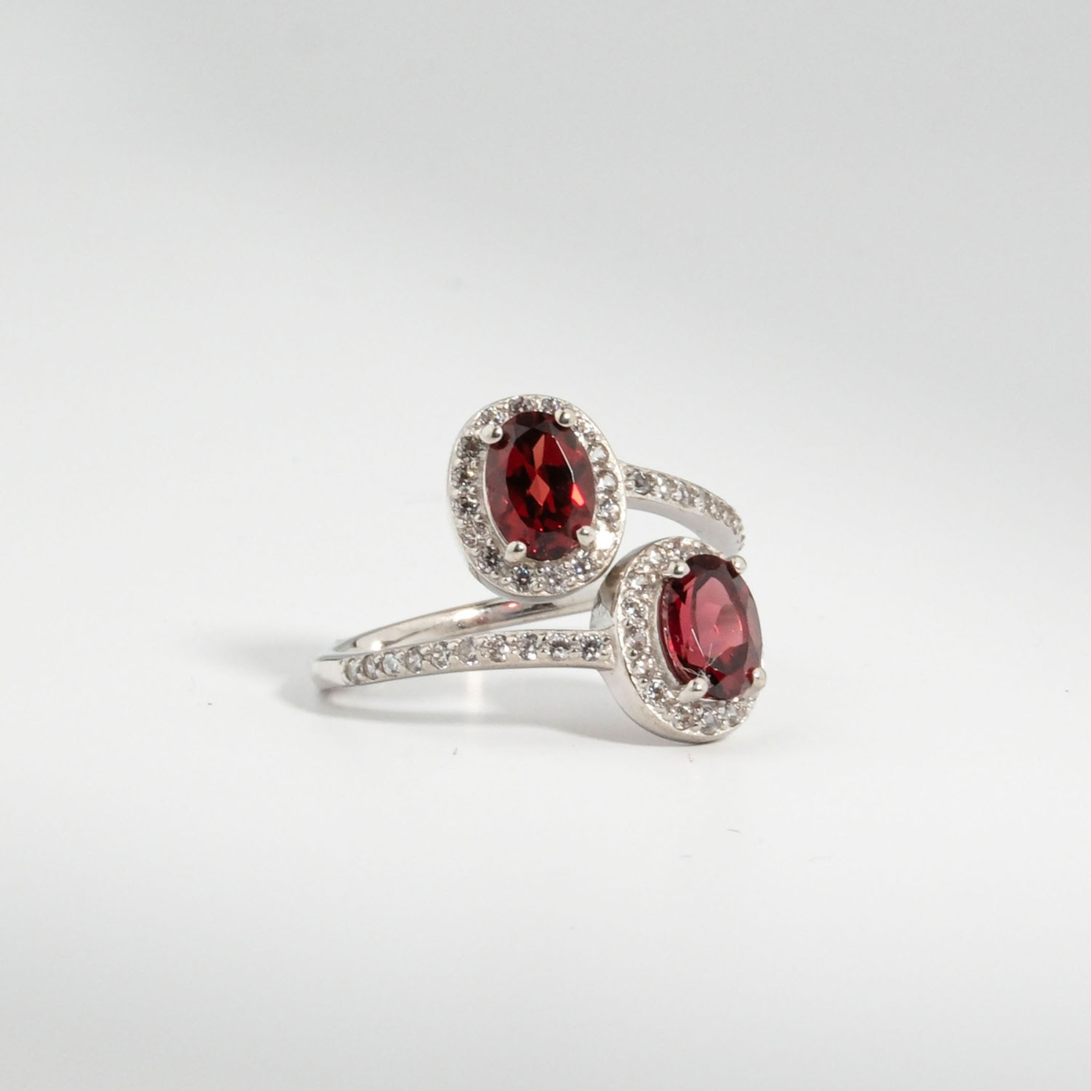 Bague bypass pour femme en argent 925 sertie de deux grenats rouges naturels entourés de zircons.