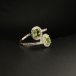 Bague bypass pour femme en argent 925 sertie de deux péridots verts naturels entourés de zircons.