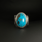 A 925 sterling silver handmade men's ring featuring a natural oval cabochon cut Nishapur turquoise gemstone with dark matrix and pyrite spots.