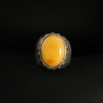 A 925 sterling silver men's ring featuring an oval cabochon cut natural yellow amber gemstone with textured band.