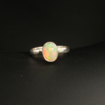 A 925 sterling silver women's ring featuring a natural oval cabochon opal gemstone with vibrant green and orange play of color.