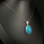 Pendentif unisex en argent 925 serti d'une turquoise naturelle taillée en cabochon avec bordure dentellée.