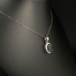 A 925 sterling silver women's pendant featuring a natural oval cabochon black opal gemstone with green play-of-color surrounded by cubic zirconia halo.