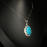 Pendentif pour femme en argent 925 serti d'une turquoise naturelle taillée en cabochon entourée de zircons.